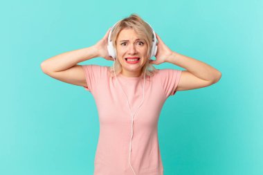 young pretty woman feeling stressed, anxious or scared, with hands on head. listening music concept