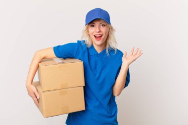 young pretty woman feeling happy and astonished at something unbelievable. package delivering concept