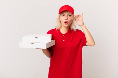 young pretty woman looking happy, astonished and surprised. pizza delivering concept