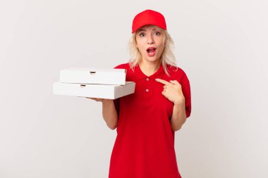 young pretty woman looking shocked and surprised with mouth wide open, pointing to self. pizza delivering concept
