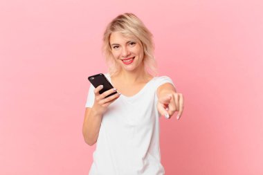 young pretty woman pointing at camera choosing you. cell concept