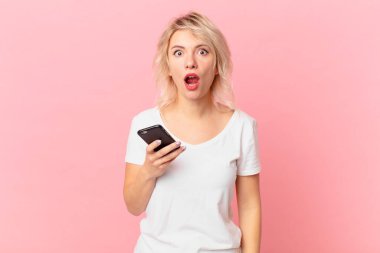 young pretty woman looking very shocked or surprised. cell concept