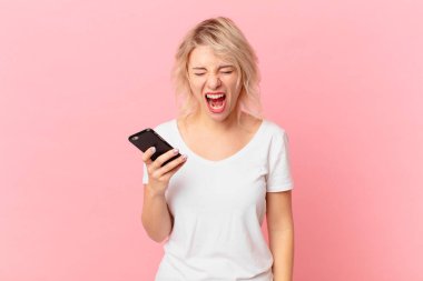 young pretty woman shouting aggressively, looking very angry. cell concept