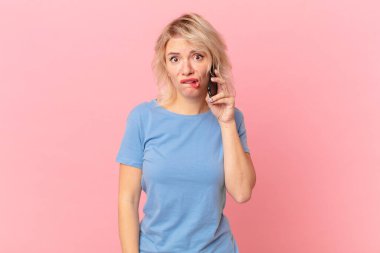 young pretty woman looking puzzled and confused. cell concept