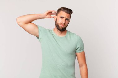 Kafası karışmış, kafası karışmış, kaşınan genç yakışıklı bir adam.