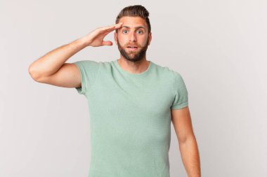 Genç yakışıklı adam mutlu, şaşkın ve şaşkın görünüyor.