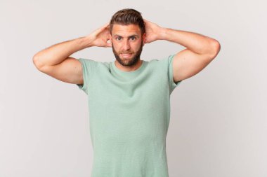 Genç ve yakışıklı adam stresli, endişeli ya da korkmuş, elleri başının üstünde.