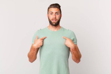 Genç yakışıklı adam mutlu hissediyor ve heyecanla kendini işaret ediyor.