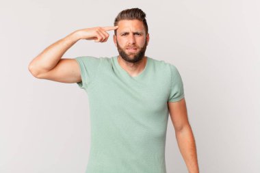 Genç yakışıklı adam kafası karışık ve şaşkın hissediyor, deli olduğunu gösteriyor.