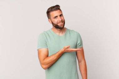 Genç yakışıklı adam neşeyle gülümsüyor, mutlu hissediyor ve bir konsept gösteriyor.
