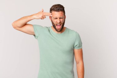 Genç yakışıklı adam mutsuz ve stresli görünüyor, intihar jesti silah işareti yapıyor.
