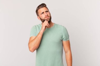 Genç yakışıklı adam düşünüyor, kuşkulu ve şaşkın hissediyor.