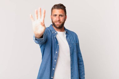 Genç yakışıklı adam gülümsüyor ve arkadaş canlısı görünüyor, dört numarayı gösteriyor.