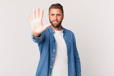 Genç yakışıklı adam gülümsüyor ve arkadaş canlısı görünüyor, beş numarayı gösteriyor.