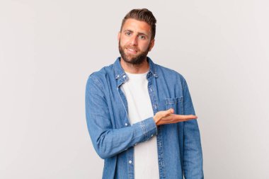 Genç yakışıklı adam neşeyle gülümsüyor, mutlu hissediyor ve bir konsept gösteriyor.