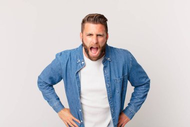 Genç yakışıklı adam agresif bir şekilde bağırıyor, çok sinirli görünüyor.