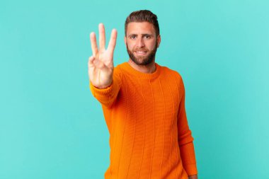 Genç yakışıklı adam gülümsüyor ve arkadaş canlısı görünüyor.