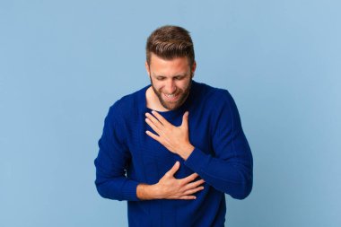 Genç yakışıklı adam komik bir şakaya yüksek sesle gülüyor.