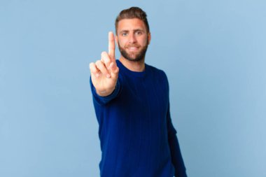 Genç yakışıklı adam gururla gülümsüyor ve kendinden emin bir numara oluyor.