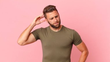 Kafası karışmış, kafası karışmış, kaşınan genç yakışıklı bir adam.