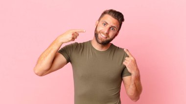 Genç ve yakışıklı bir adam, kendine güvenerek gülümsüyor.