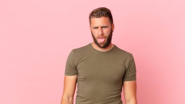 Genç yakışıklı adam iğreniyor, sinirleniyor ve dilini çıkarıyor.