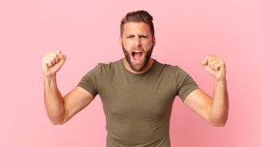 Genç yakışıklı adam sinirli bir ifadeyle agresif bir şekilde bağırıyor.