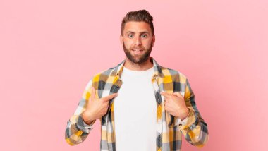 Genç yakışıklı adam mutlu hissediyor ve heyecanla kendini işaret ediyor.