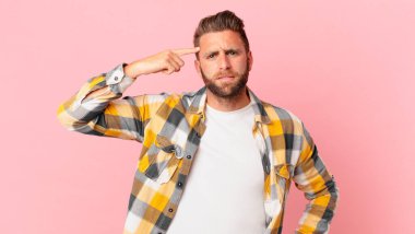 Genç yakışıklı adam kafası karışık ve şaşkın hissediyor, deli olduğunu gösteriyor.