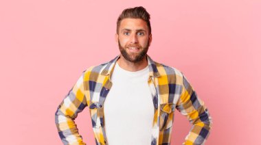 Genç yakışıklı adam mutlu ve hoş bir şekilde şaşırmış görünüyor.