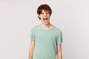 Genç yakışıklı adam agresif bir şekilde bağırıyor, çok sinirli görünüyor.