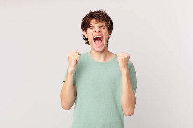 Genç yakışıklı adam sinirli bir ifadeyle agresif bir şekilde bağırıyor.