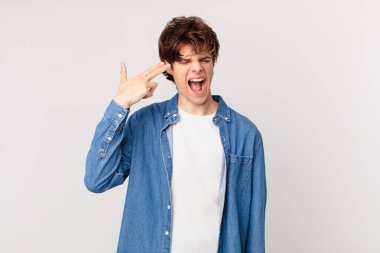 Genç yakışıklı adam mutsuz ve stresli görünüyor, intihar jesti silah işareti yapıyor.