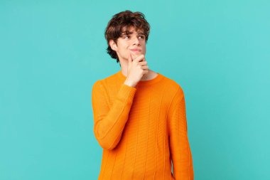 Genç yakışıklı adam düşünüyor, kuşkulu ve şaşkın hissediyor.