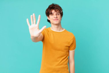 Genç yakışıklı adam gülümsüyor ve arkadaş canlısı görünüyor, beş numarayı gösteriyor.