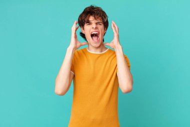 Genç yakışıklı adam ellerini havaya kaldırarak bağırıyor.