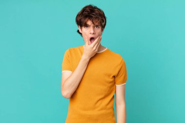 Ağzı ve gözleri açık ve eli çenesinde genç yakışıklı bir adam.