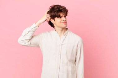 Kafası karışmış, kafası karışmış, kaşınan genç yakışıklı bir adam.