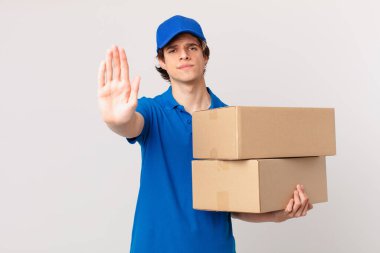 Paket teslimatçısı ciddi görünüyor. Avuç içi açık jest yapıyor.