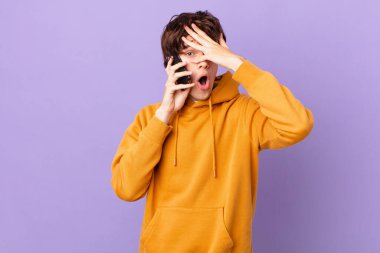 Bir hücreyi tutan genç adam şok olmuş, korkmuş ya da korkmuş görünüyor.