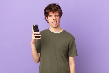 Bir hücreyi tutan genç adam iğrenmiş ve sinirlenmiş hissediyor ve dilini dışarı çıkarıyor.