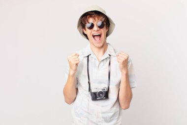 Genç gezgin ya da turist şokta, gülüyor ve başarıyı kutluyor.