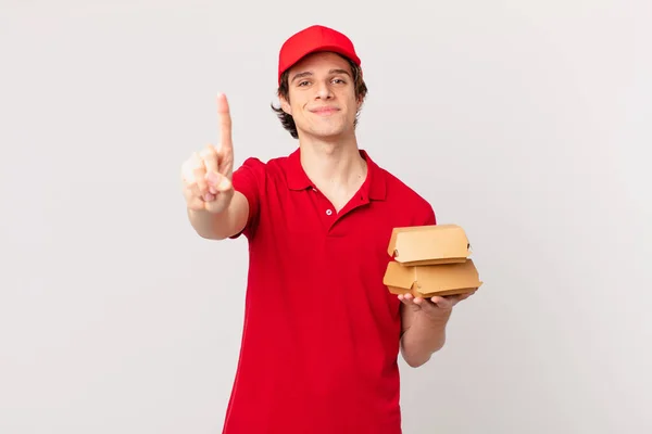 Burger Dostawy Człowiek Uśmiecha Się Wygląda Przyjaźnie Pokazując Numer Jeden — Zdjęcie stockowe