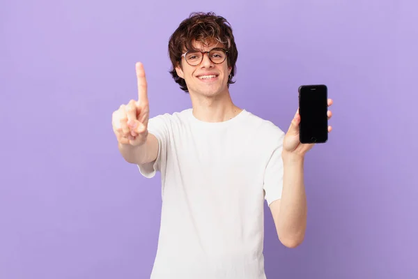 Young Man Smiling Looking Friendly Showing Number One Holding Cell — Zdjęcie stockowe