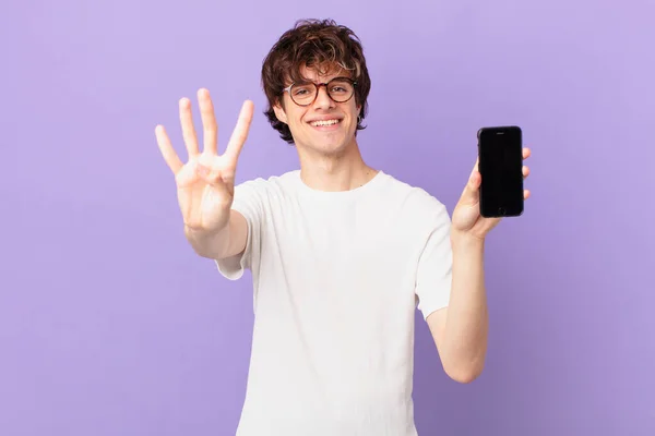 Young Man Smiling Looking Friendly Showing Number Four Holding Cell — Stockfoto