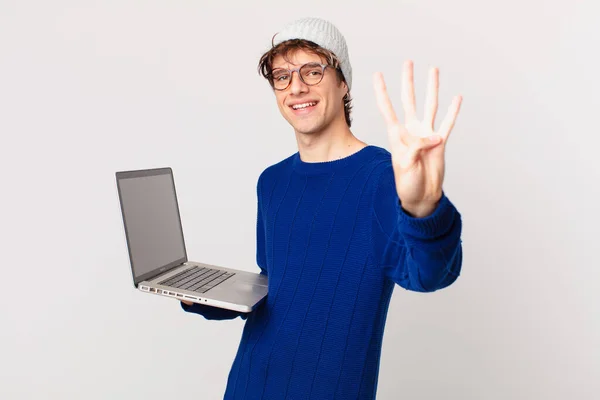 Młody Człowiek Laptopem Uśmiechnięty Przyjazny Pokazując Numer Cztery — Zdjęcie stockowe