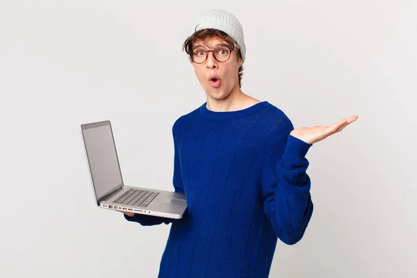 Молодой Человек Ноутбуком Выглядит Удивленным Шокированным Челюстью Упал Держа Объект — стоковое фото