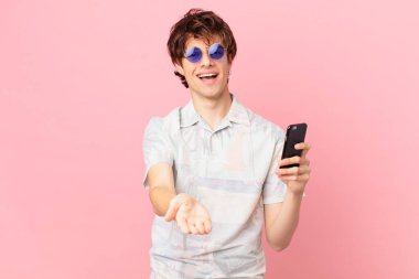 Cep telefonlu genç adam mutlu bir şekilde gülümsüyor ve bir konsept sunuyor.