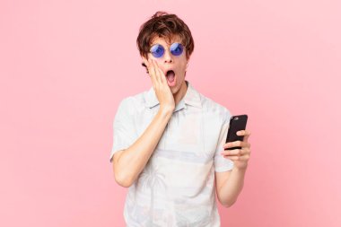 Cep telefonlu genç adam şok olmuş ve korkmuş hissediyor.