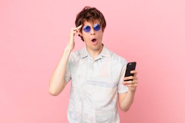 Cep telefonlu genç adam şaşırmış görünüyor, yeni bir düşünce, fikir ya da konsept keşfediyor.
